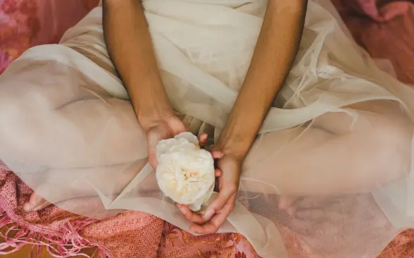 mujer-sentada-en-el-suelo-cruzada-de-piernas-cogiendo-una-rosa