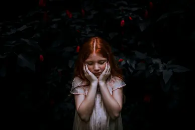 niña-pelirroja-con manos-en-el-rostro-y-fondo-oscuro